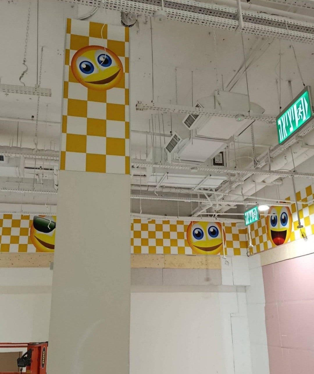 Yellow checks and illustrated faces decorate the upper walls of a commercial interior.